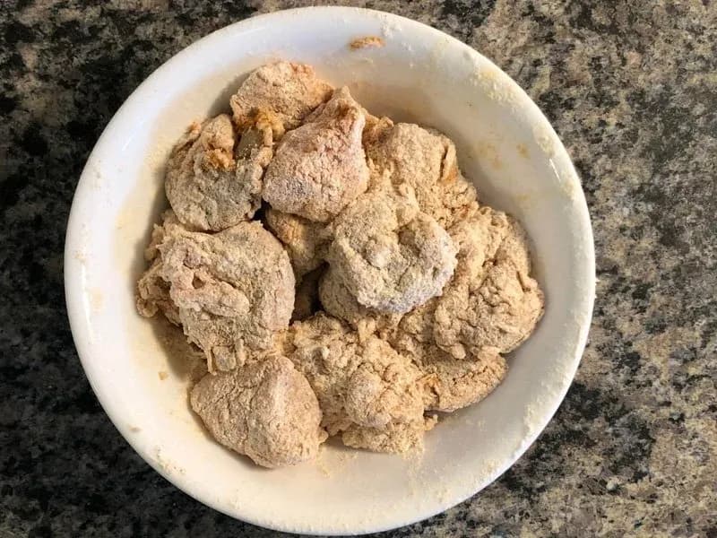 Marinated chicken and shrimp coated in blackening spice mixture in a white bowl, ready for frying.