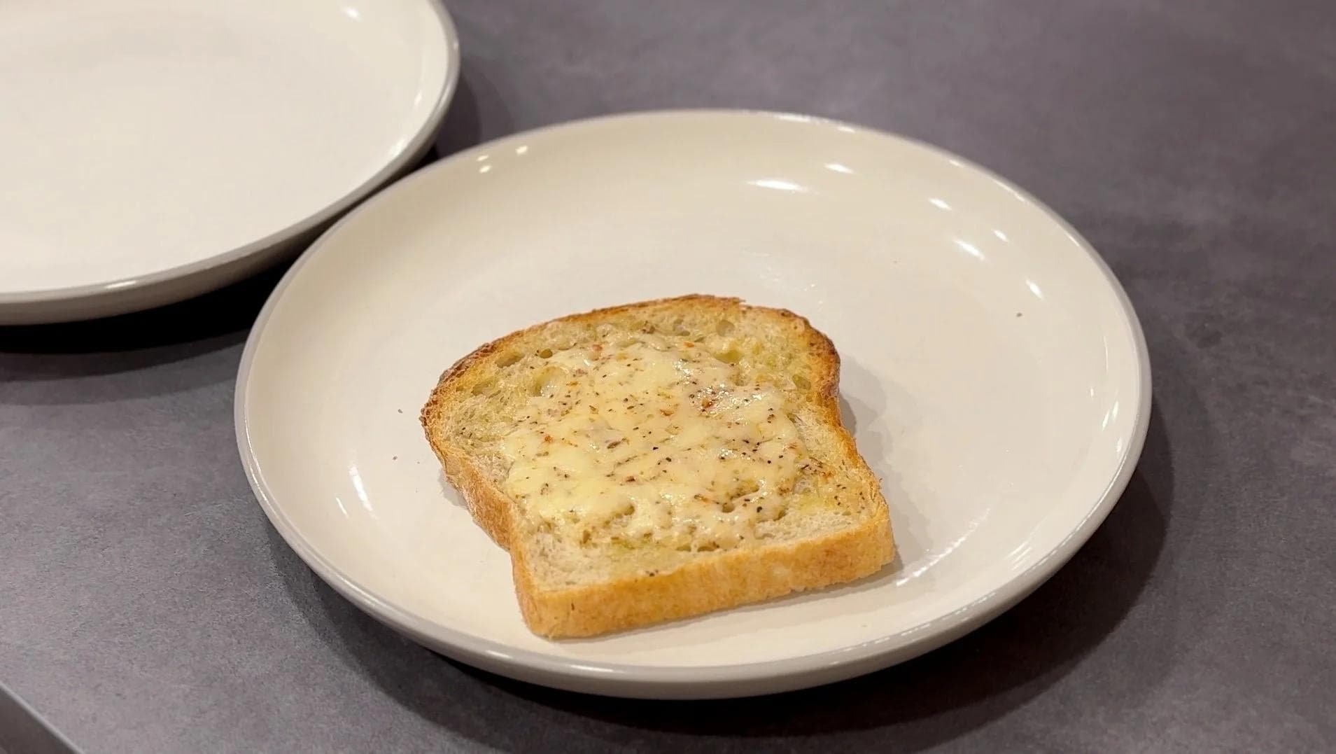 Golden toasted sourdough bread slice with herbs on a white plate, ready for mushroom topping.