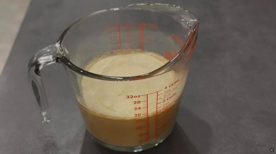 Ginger chai ice cream mixture in a measuring cup before freezing, showing blended ingredients with layered color separation.