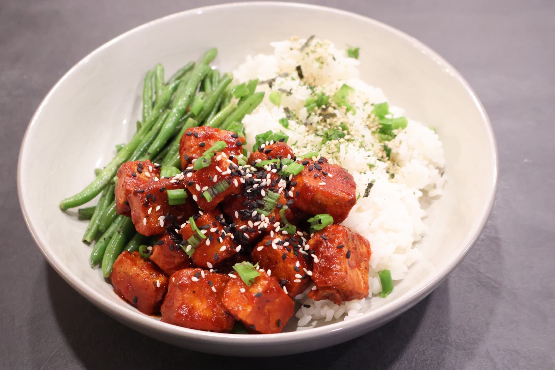 Korean-style crispy air fryer tofu bowl with green beans, white rice, and sesame seeds garnish.