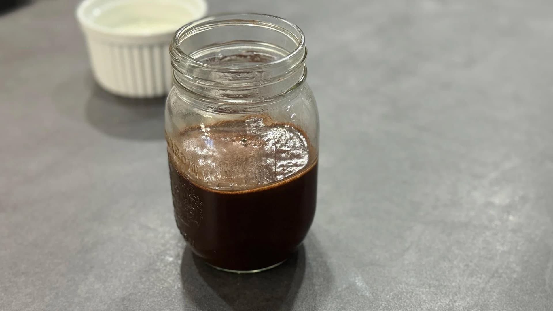 Homemade chocolate sauce stored in a mason jar in the refrigerator.