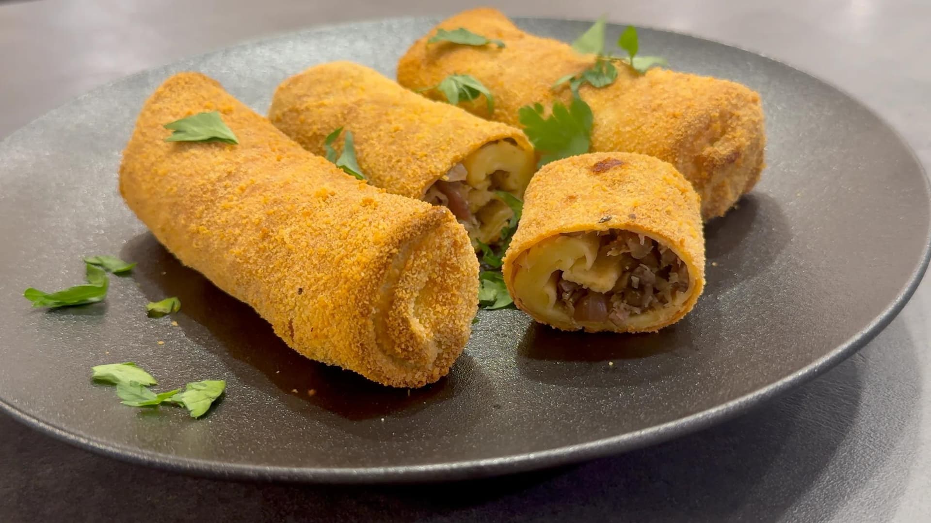 Golden-brown air fryer krokiety Polish croquettes on a dark plate, garnished with chopped green onions.