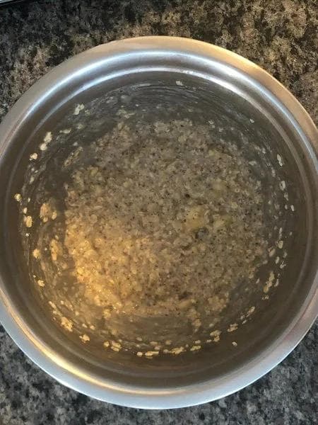 Mashed banana and oats mixed with milk in a metal bowl with chocolate chips folded throughout.