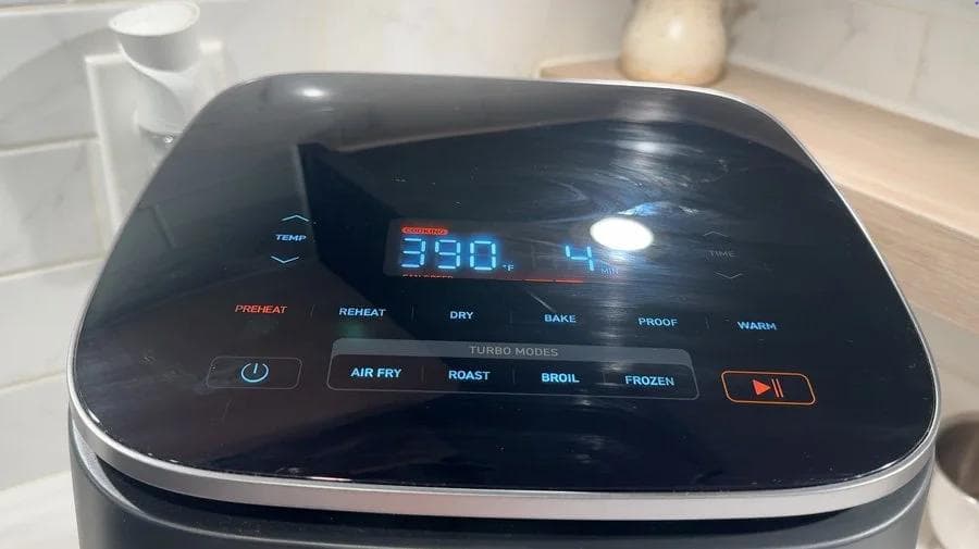 Air fryer display showing 390°F temperature for preheating potatoes in kitchen.
