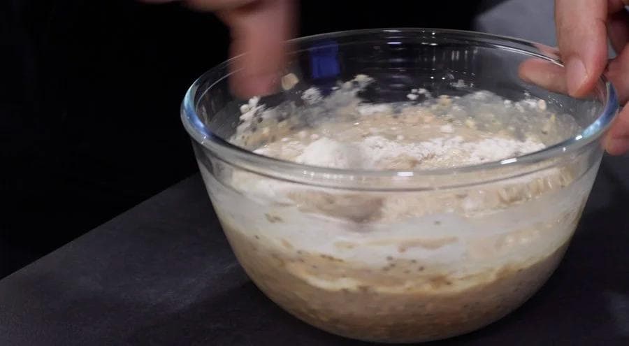 Mixed overnight oats batter with oats, milk, and protein powder in a clear glass bowl.