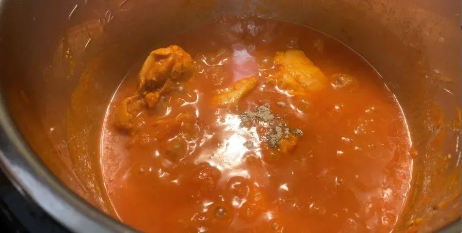 Chicken Tikka Masala sauce simmering in Instant Pot after adding honey and cardamom, rich orange-brown color with chicken pieces visible.