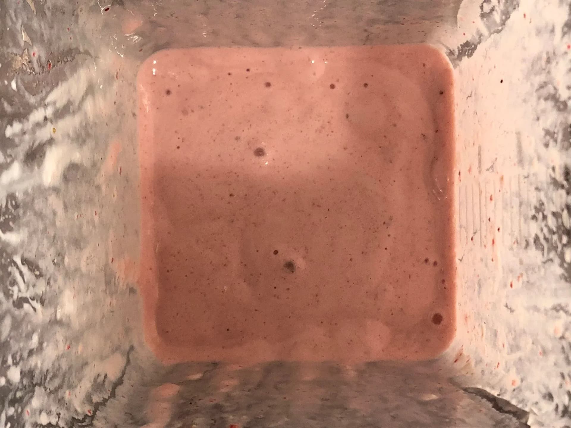 Blended strawberry cheesecake smoothie with a smooth, creamy pink texture in a blender.