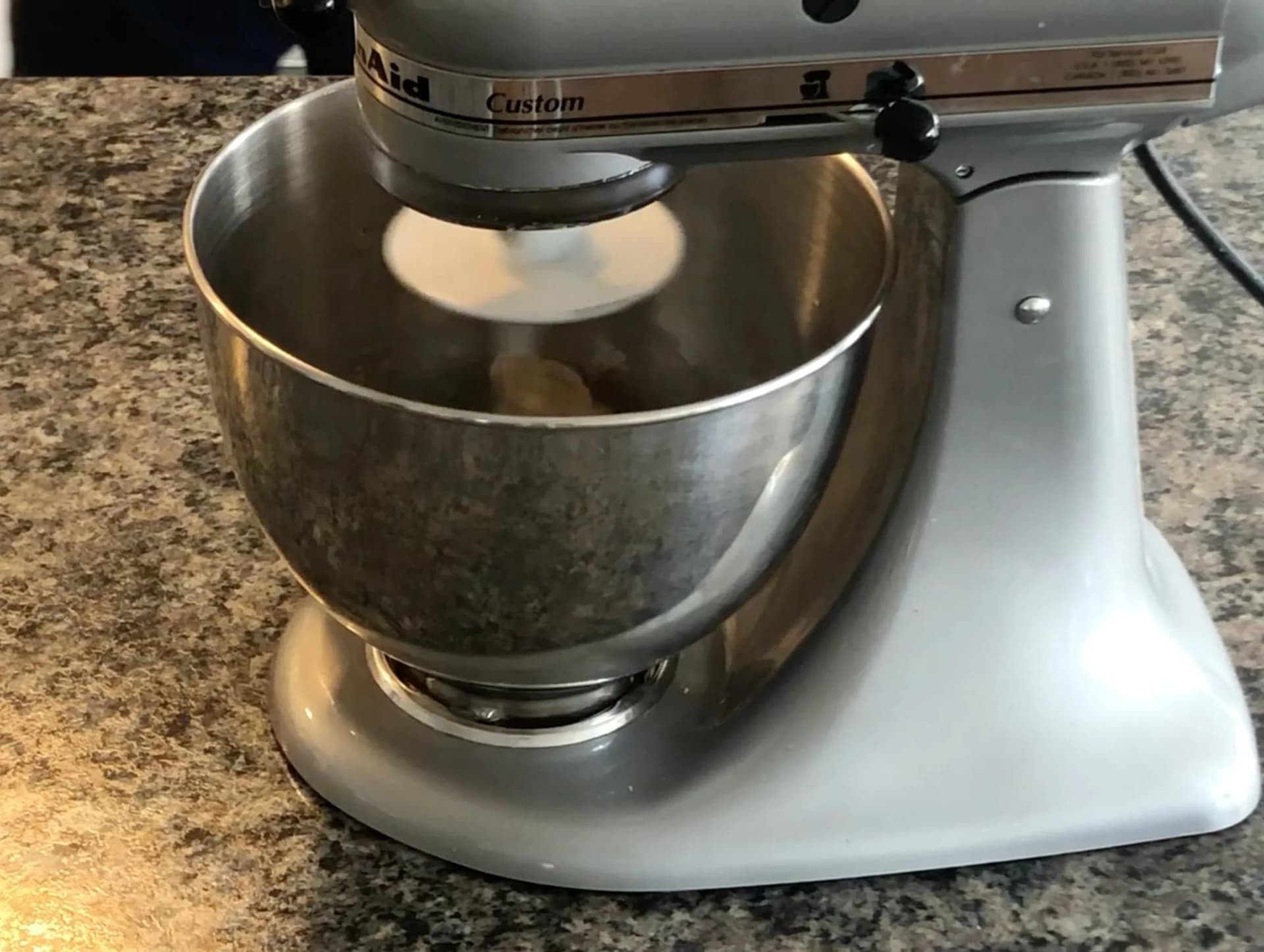 Stand mixer with stainless steel bowl kneading dough for paratha, showing soft dough texture during mixing process.