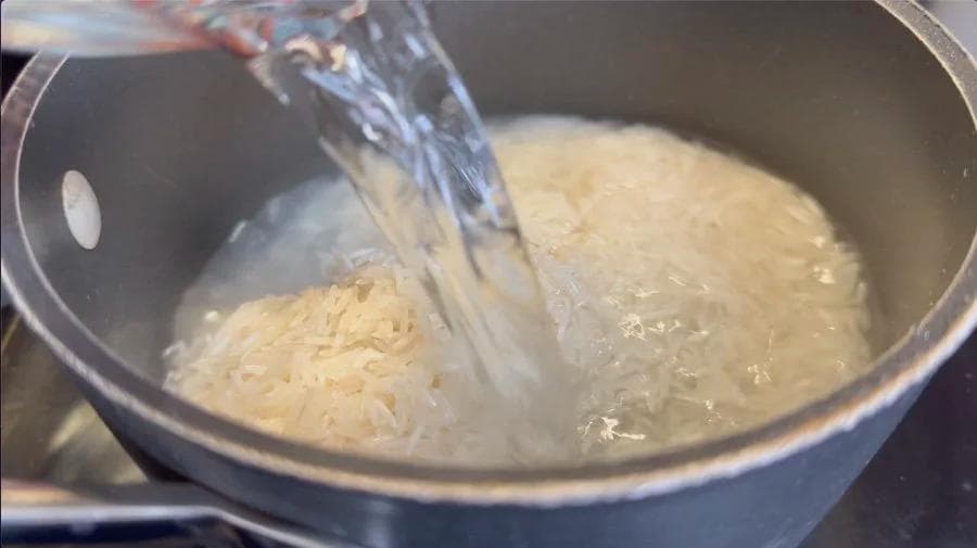 Water being poured into a pot of rinsed rice for cooking cilantro-lemon rice.