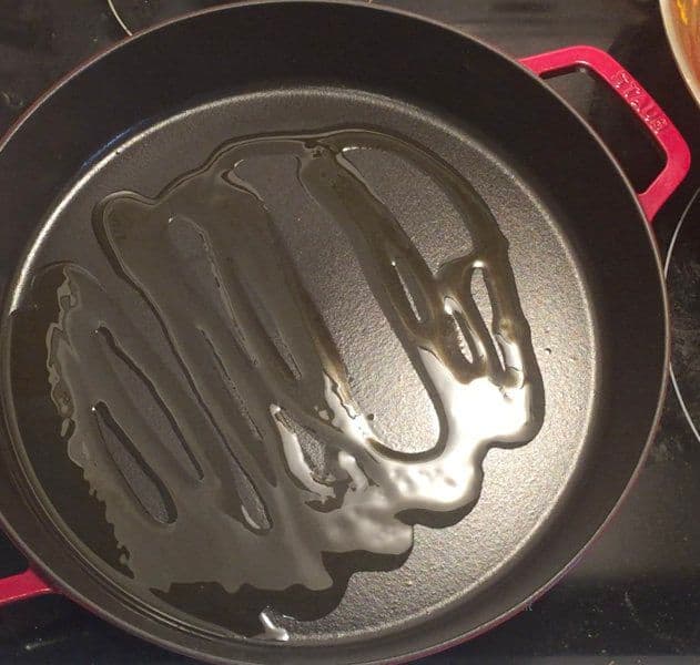 Cast iron skillet with decorative chicken-shaped mold containing cooked chicken tikka with caramelized surface.