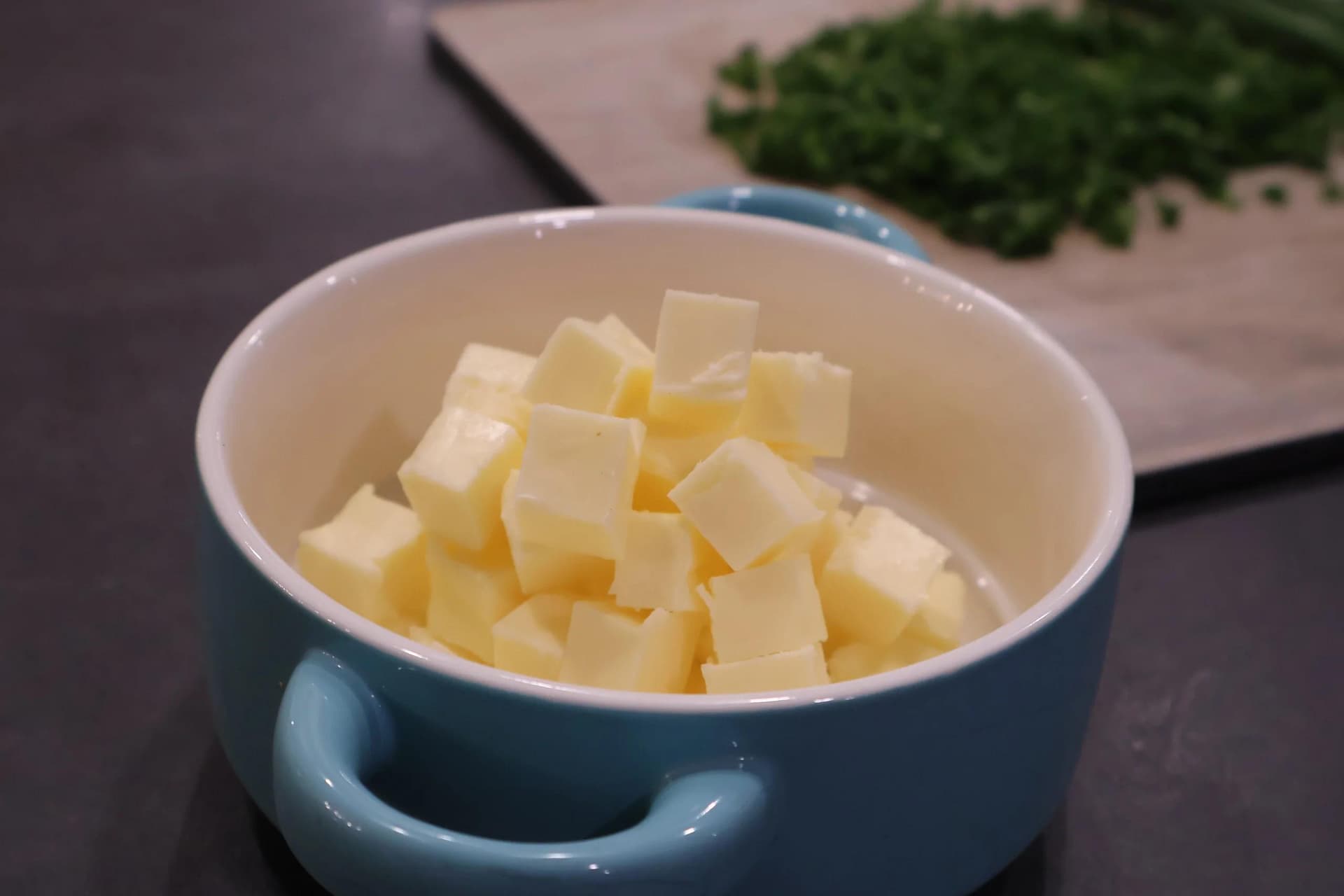 Cubed room temperature butter in a blue ceramic bowl.