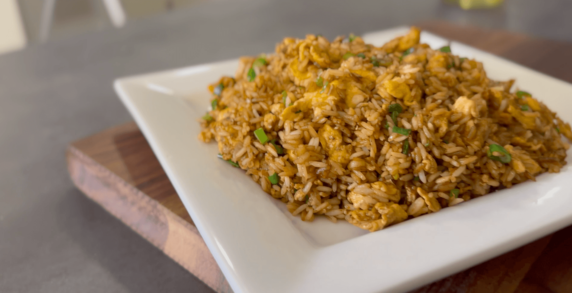 Fluffy golden egg fried rice with peas and green onions served on a white plate.