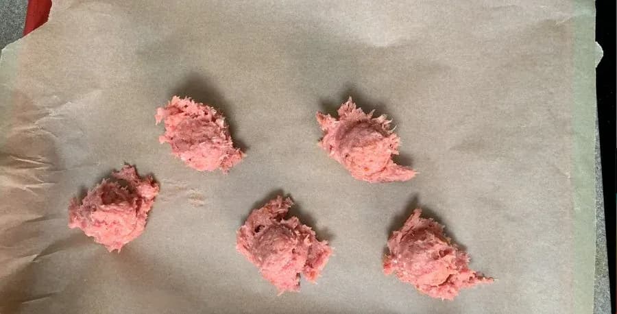 Five pink breakfast patties on parchment paper, formed and ready to chill.