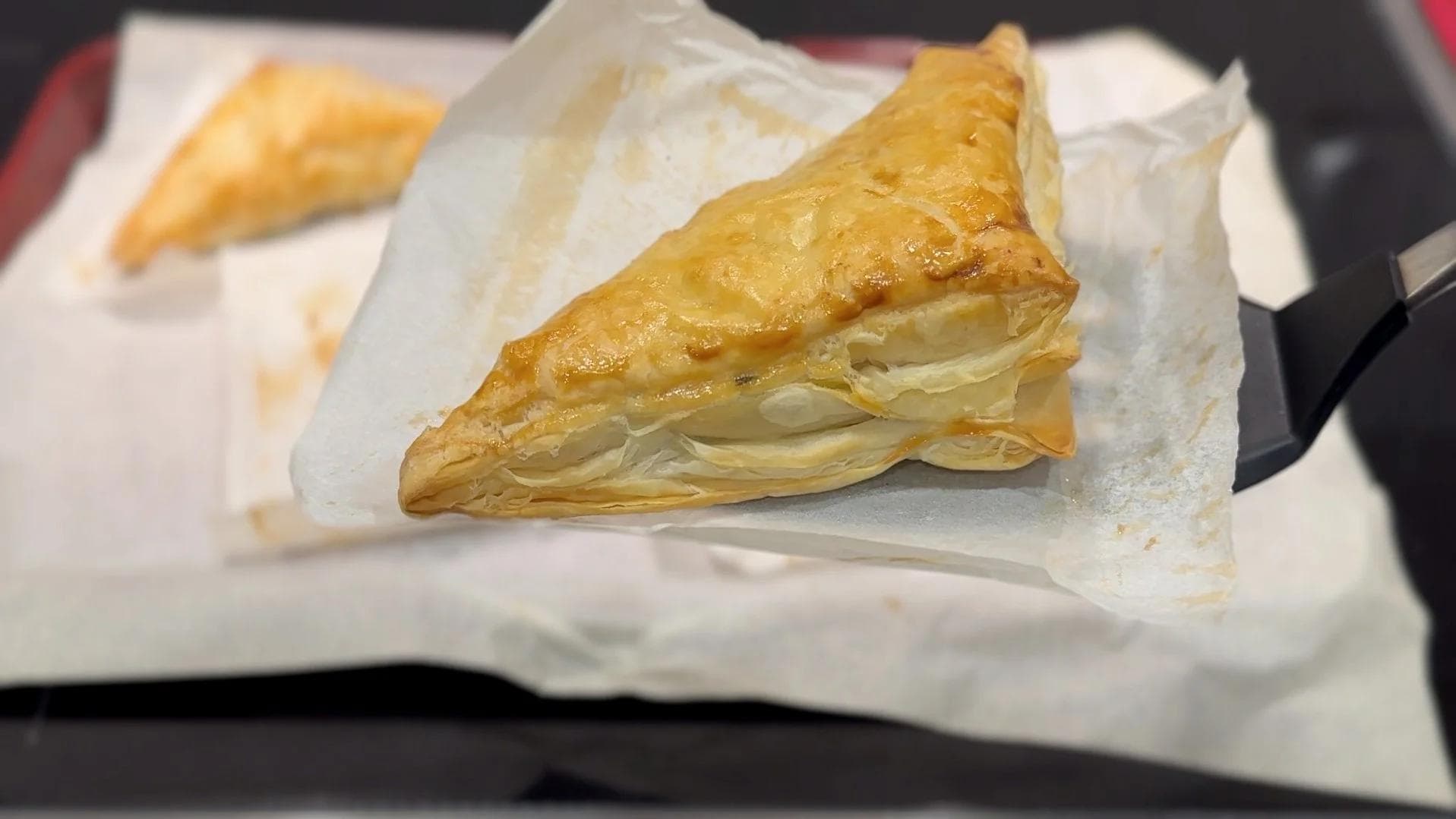 Golden-brown mushroom puff pastry on white parchment paper, showing crispy, flaky layers.