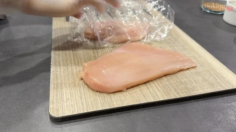 Pounded chicken breast on a wooden cutting board, ready to be seasoned.