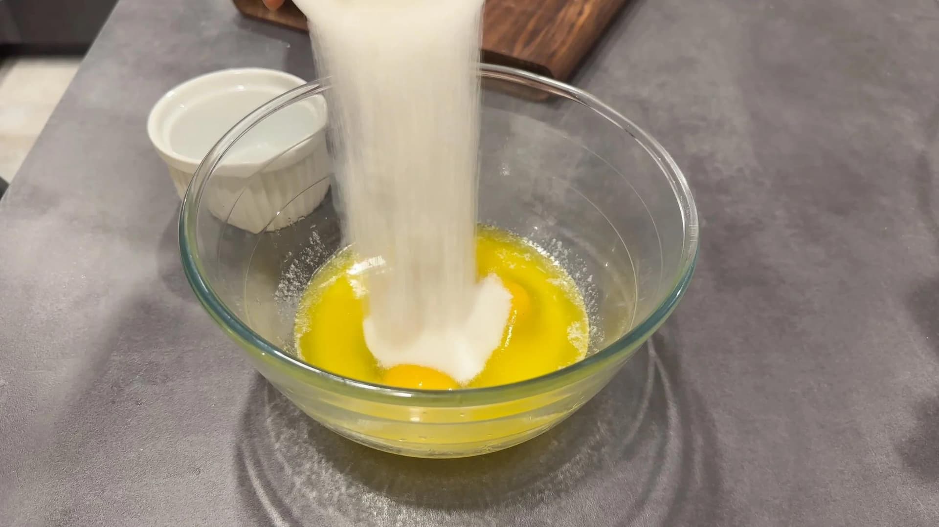 Pouring milk into a bowl with melted butter and eggs for banana brownie batter.