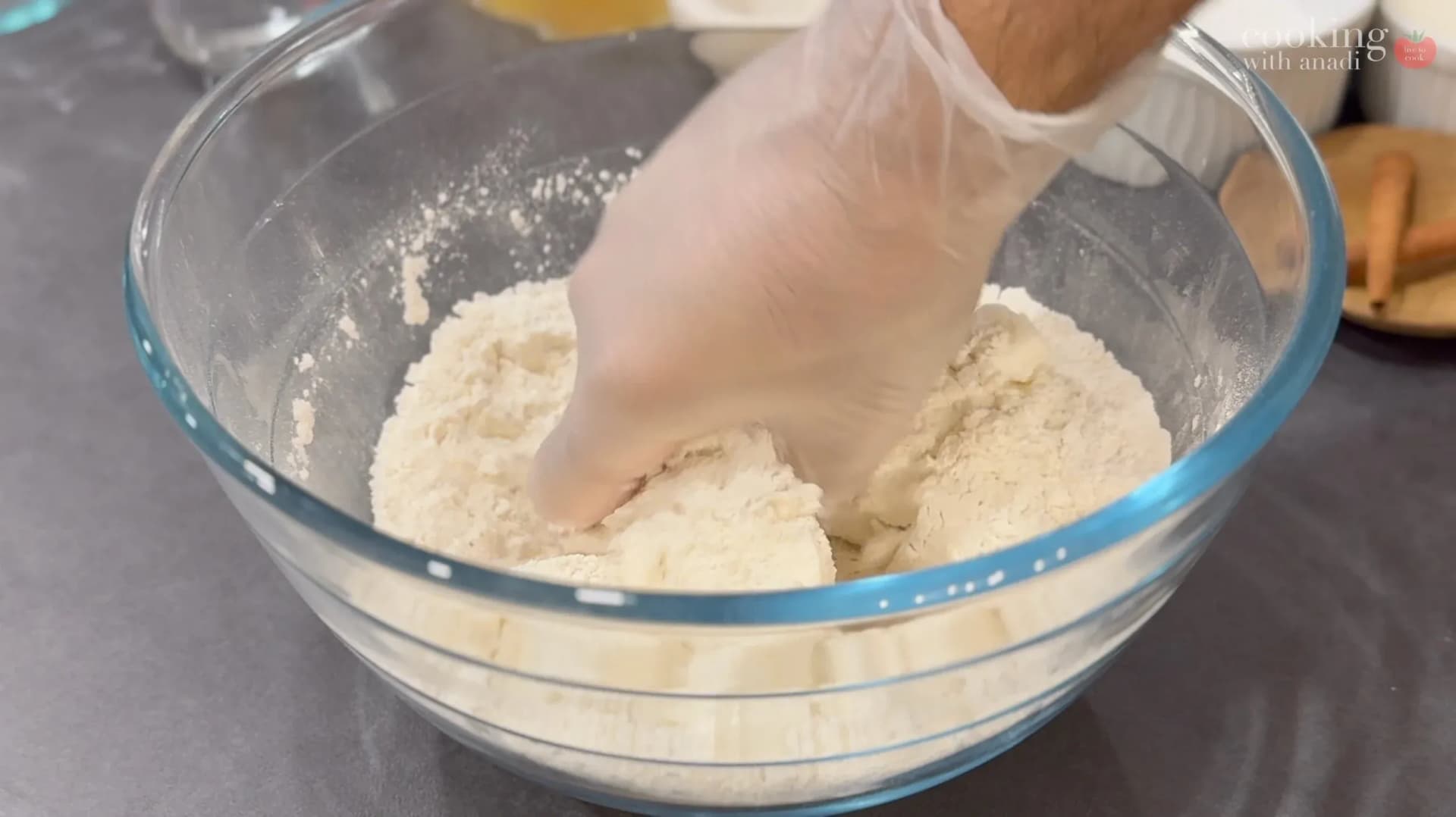 Hand mixing flour and shortening in a glass bowl for pie dough