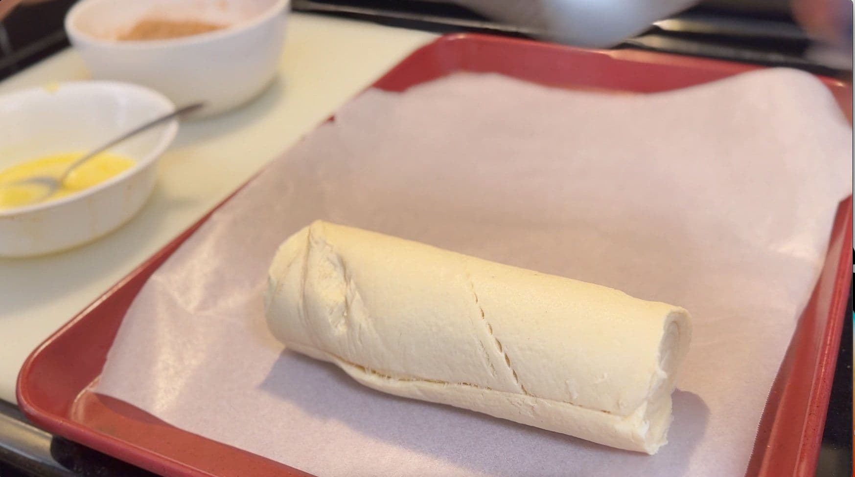Rolled crescent roll dough with cinnamon sugar filling on parchment paper, ready for air frying.
