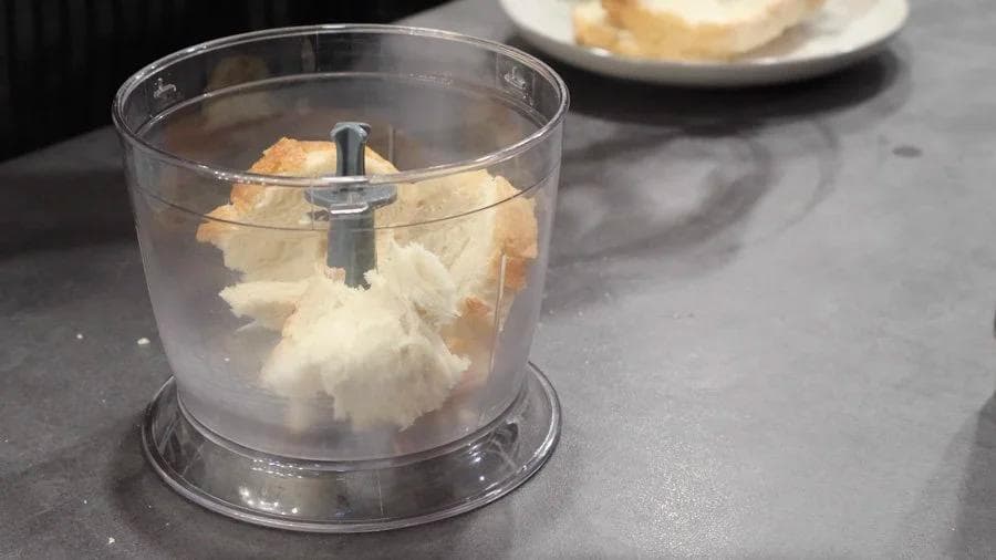 Breadcrumbs being blended in a food processor for chicken nugget breading.