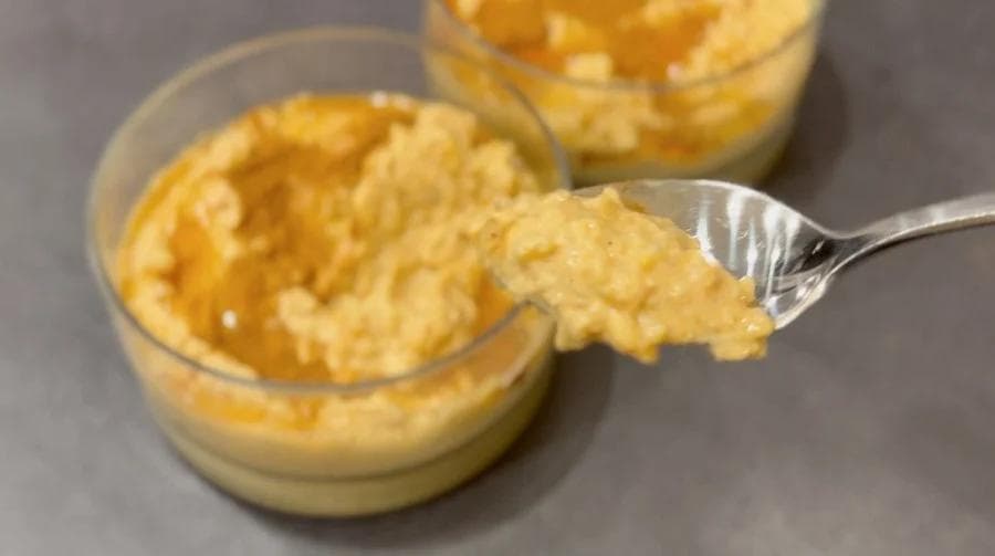 Creamy pumpkin rice pudding in glass bowls with a spoon showing the thick, smooth texture.