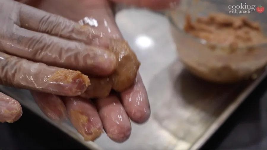Hands shaping ground chicken mixture into flattened nugget balls for air frying.