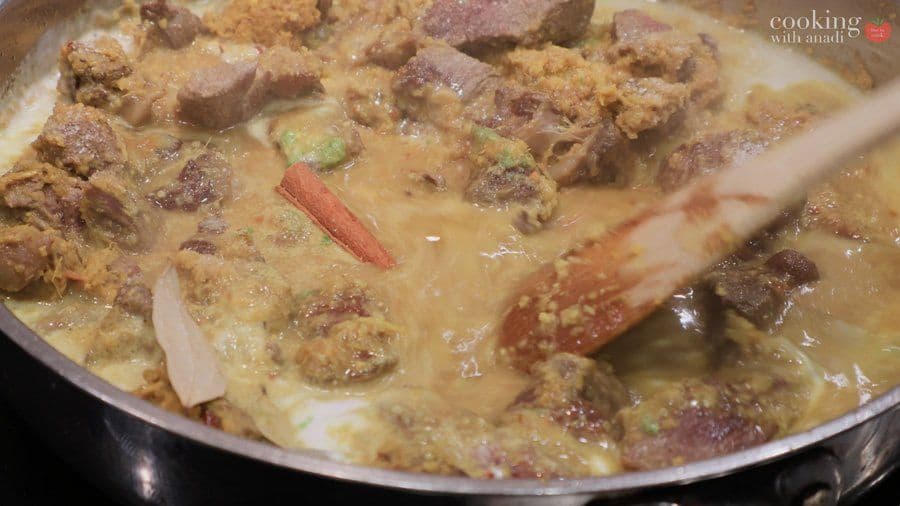 Beef rendang simmering in creamy coconut sauce with spices in a pan, ready for extended cooking.