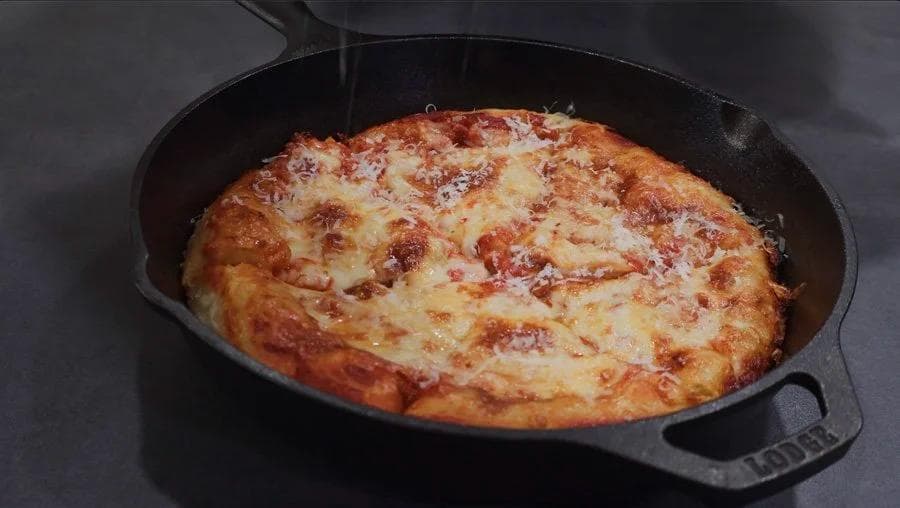 Cast iron skillet pizza with melted cheese and golden-brown crust fresh from the oven.