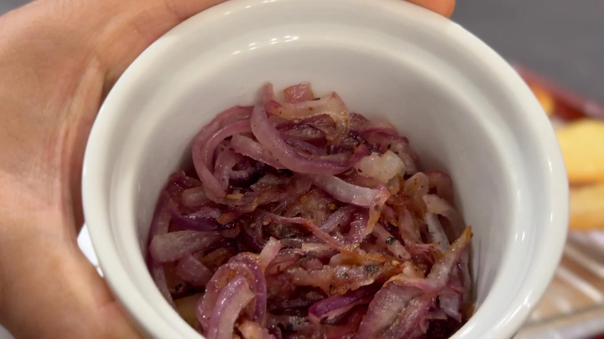 Caramelized red onions in a white bowl, a key topping for bacon cheeseburger sliders.