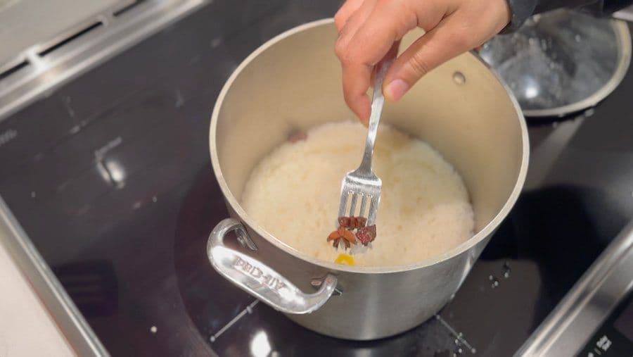 Stirring creamy arroz con leche rice pudding with a fork in a pot on the stove.