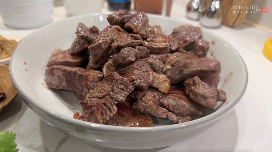 Seared beef cubes in a white bowl, browned on all sides for Balinese beef rendang.