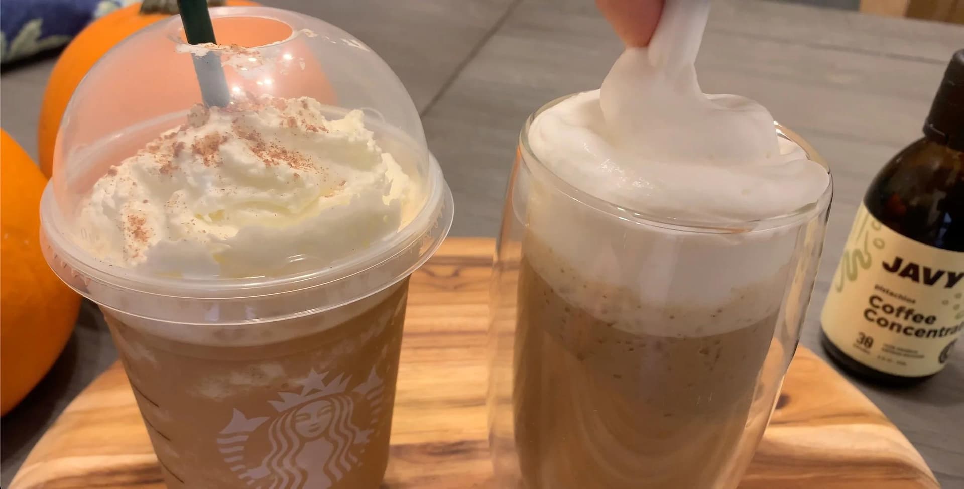 Homemade pumpkin spice frappuccino topped with whipped cream and cinnamon, served in a glass next to ingredients.