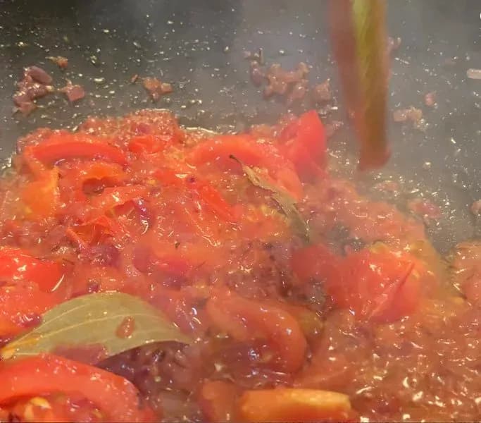 Delhi style chole curry simmering in tomato-based gravy with red peppers and spices.