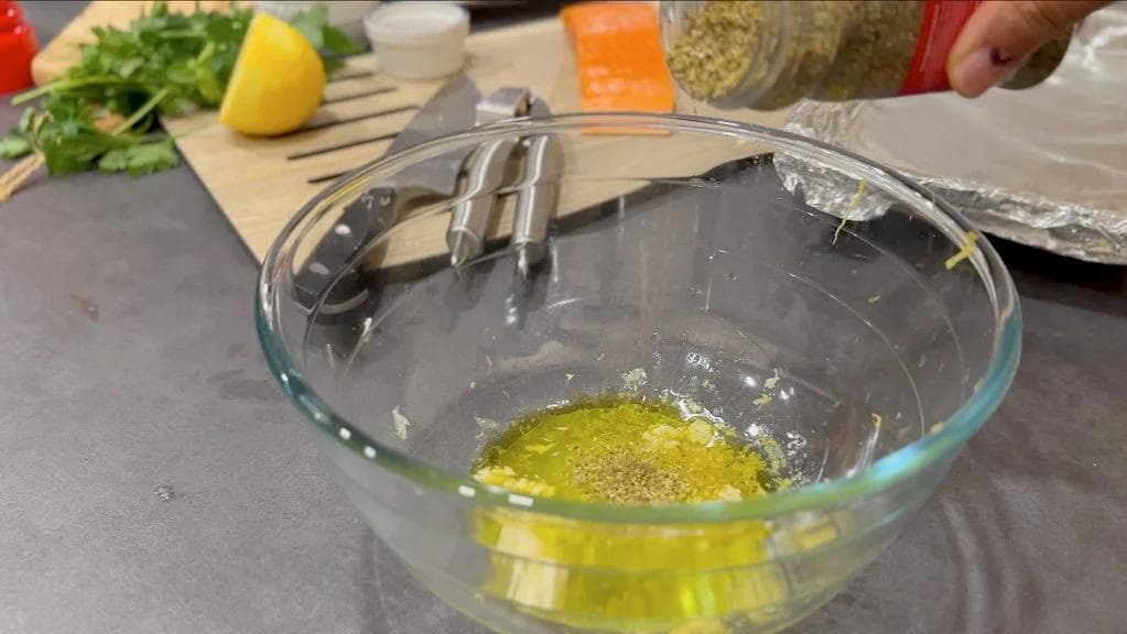 Lemon herb marinade with olive oil, lemon juice, and herbs mixed in a glass bowl.