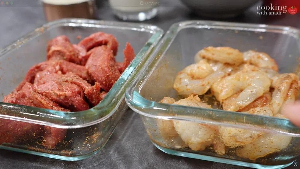 Seasoned steak strips and shrimp in separate glass baking dishes, prepared for cooking Cajun Alfredo pasta.