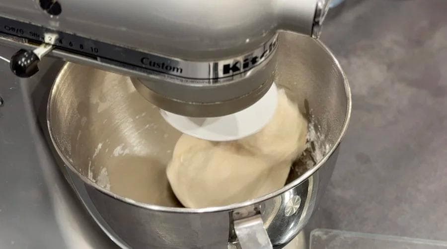 Stand mixer with flat beater mixing smooth dough for Canadian Beavertails in stainless steel bowl.