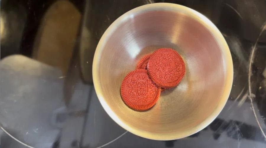 Two crushed red velvet cookies in a white bowl, ready to be mixed into the latte.