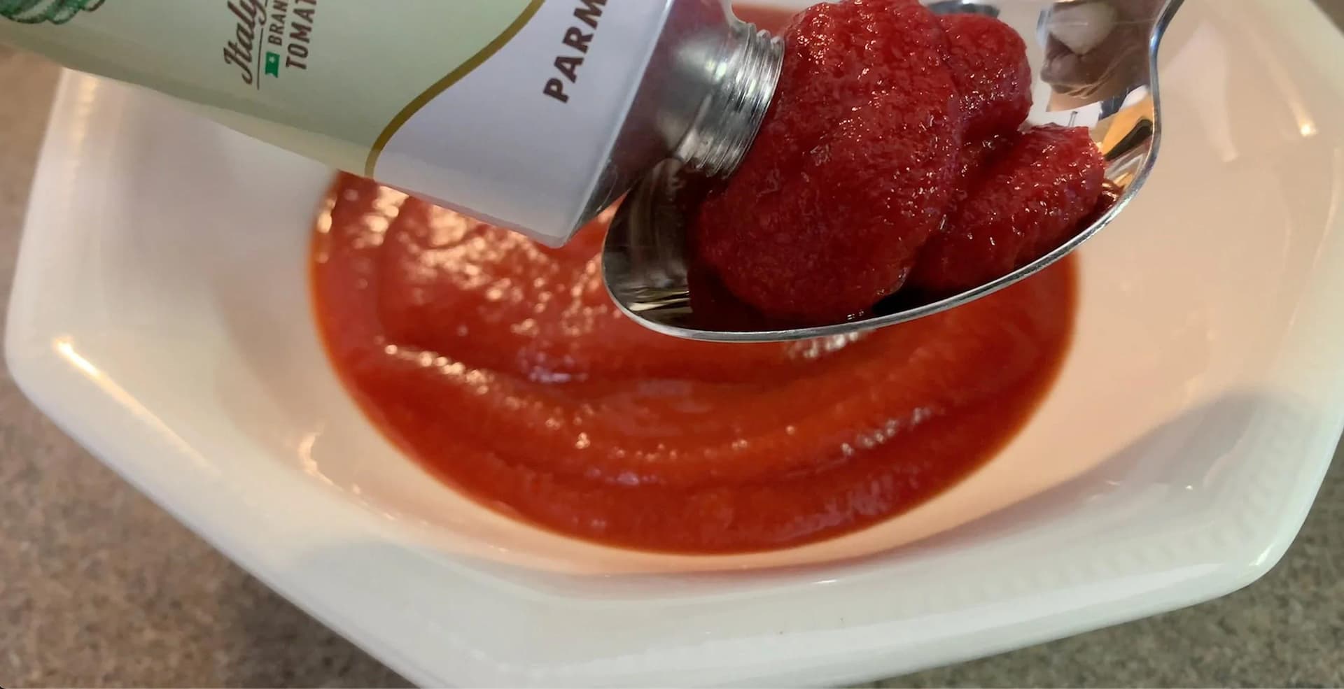 No-cook makhani sauce in white bowl with spoon of raspberries and jar of ingredients.