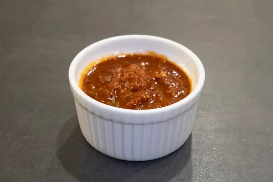Homemade salsa roja in a white ramekin, showing a smooth, glossy red-brown sauce with a mild appearance.