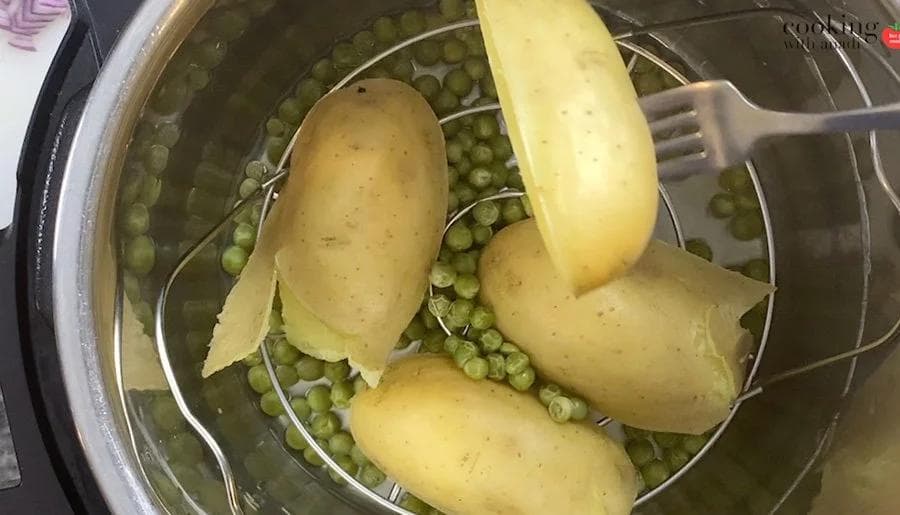 Boiled potatoes and peas in a colander being drained in an Instant Pot.