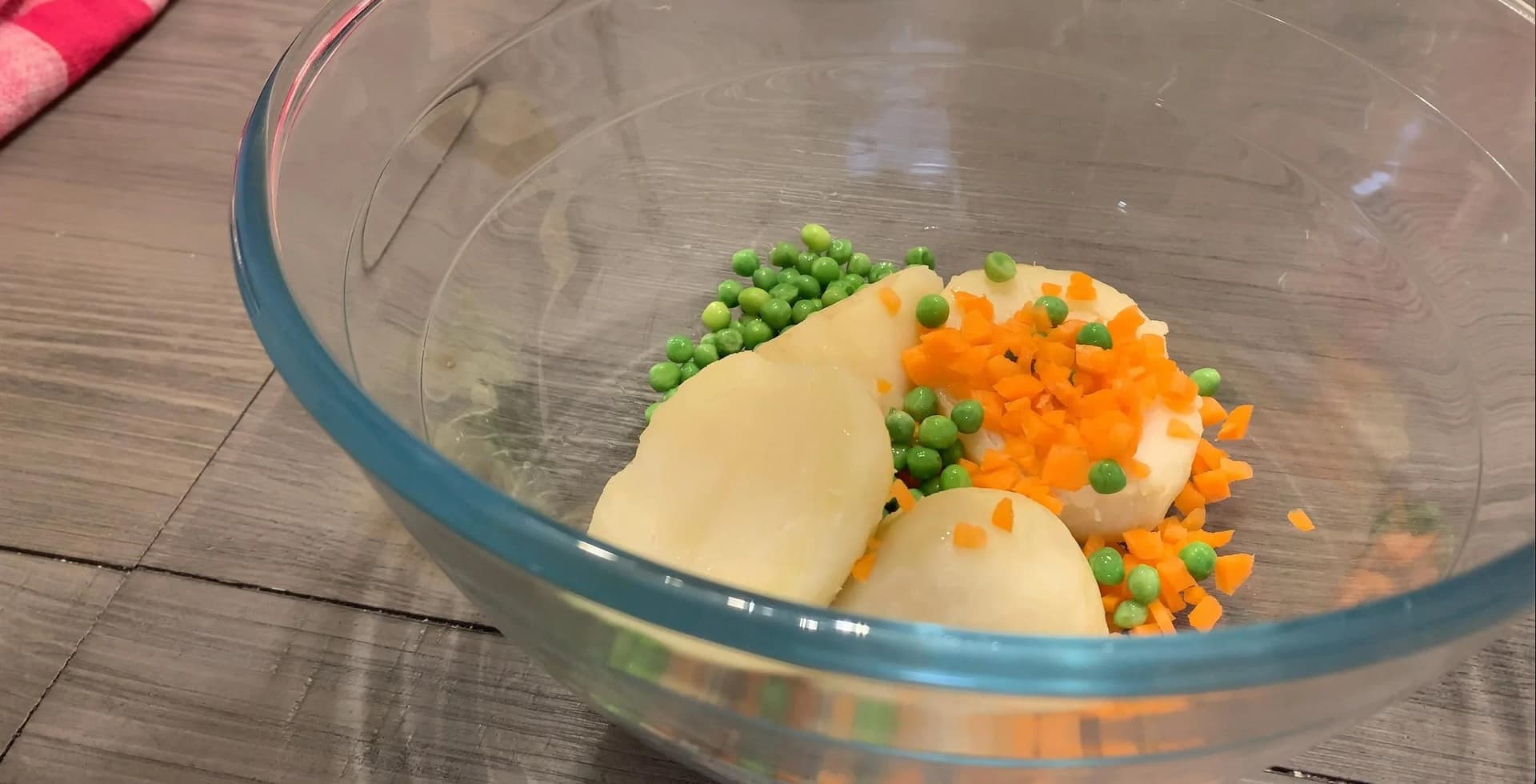 Boiled potatoes, peas, and diced carrots in a glass bowl before mixing for McAloo Tikki filling.