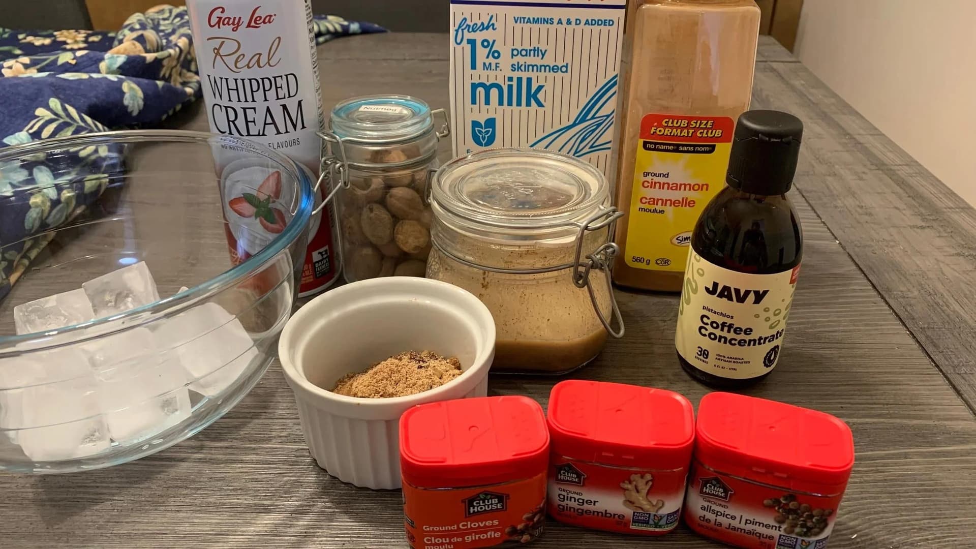 Ingredients for homemade pumpkin spice frappuccino including whipped cream, milk, spices, coffee concentrate, and peanut butter.