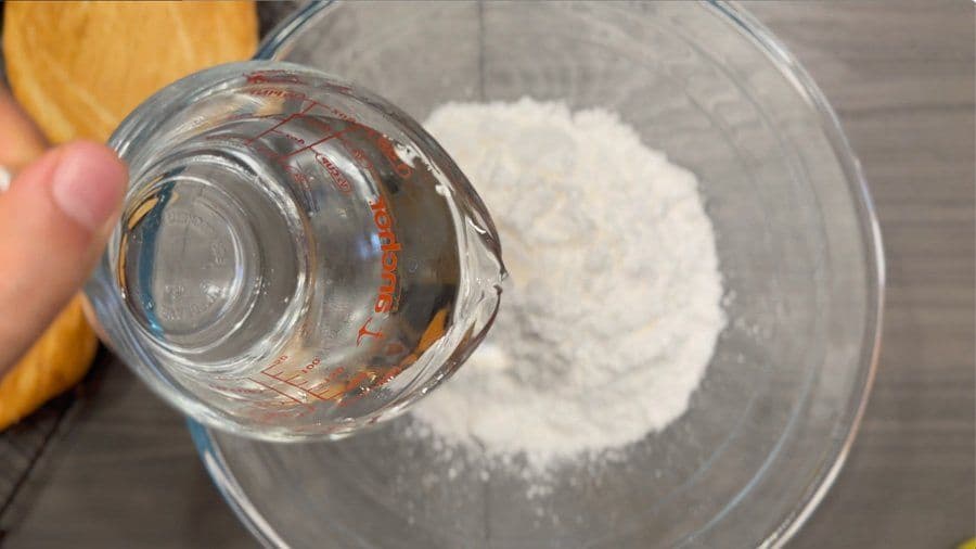 Pouring vanilla extract into a bowl of powdered sugar for cookie icing.