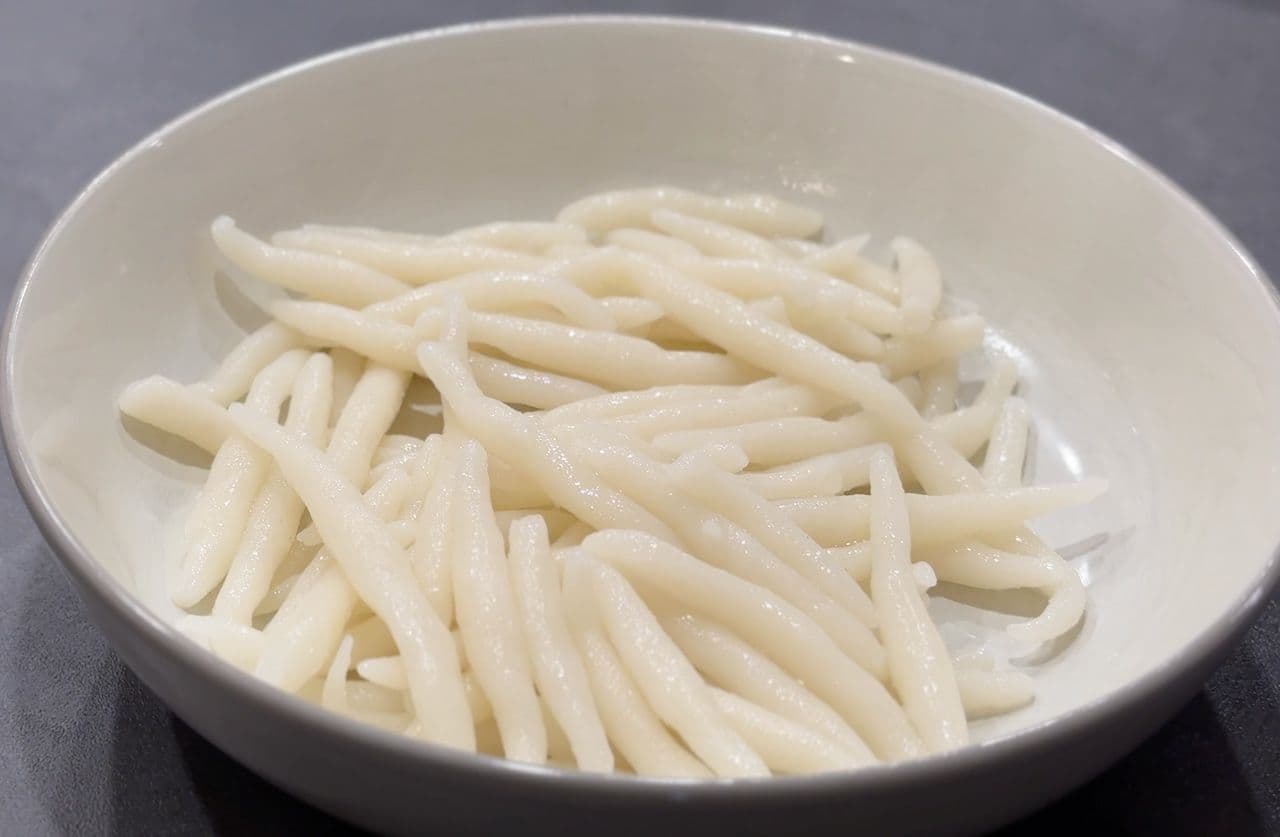 Cooked rice pin noodles piled in a white bowl, showing their thin, smooth texture.