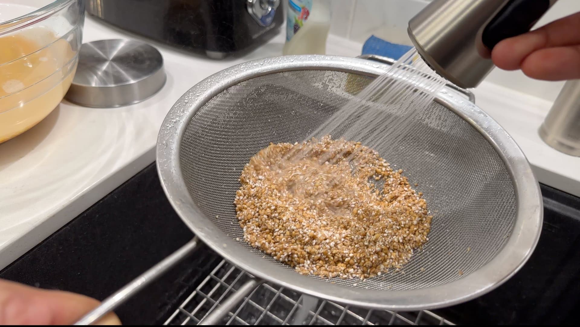 Washed lentils and rice in a fine mesh sieve during preparation for Pakistani lamb haleem.