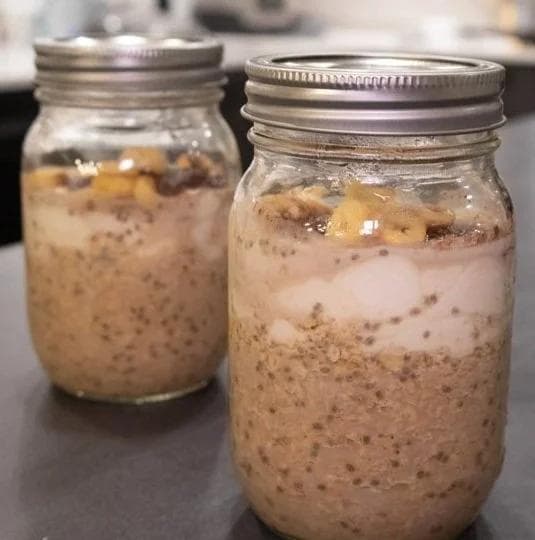 Two mason jars of tiramisu overnight oats with layered chocolate and vanilla mixture and visible chia seeds.
