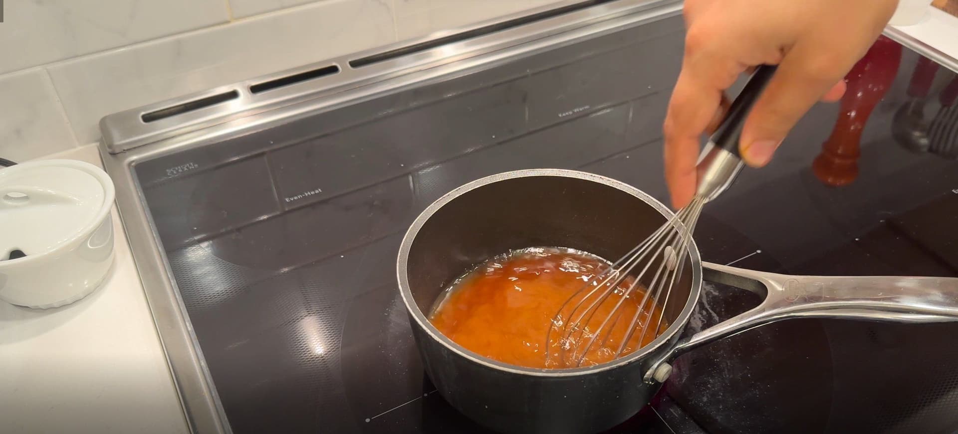 Whisking dissolved brown sugar and water mixture in a saucepan on the stovetop.