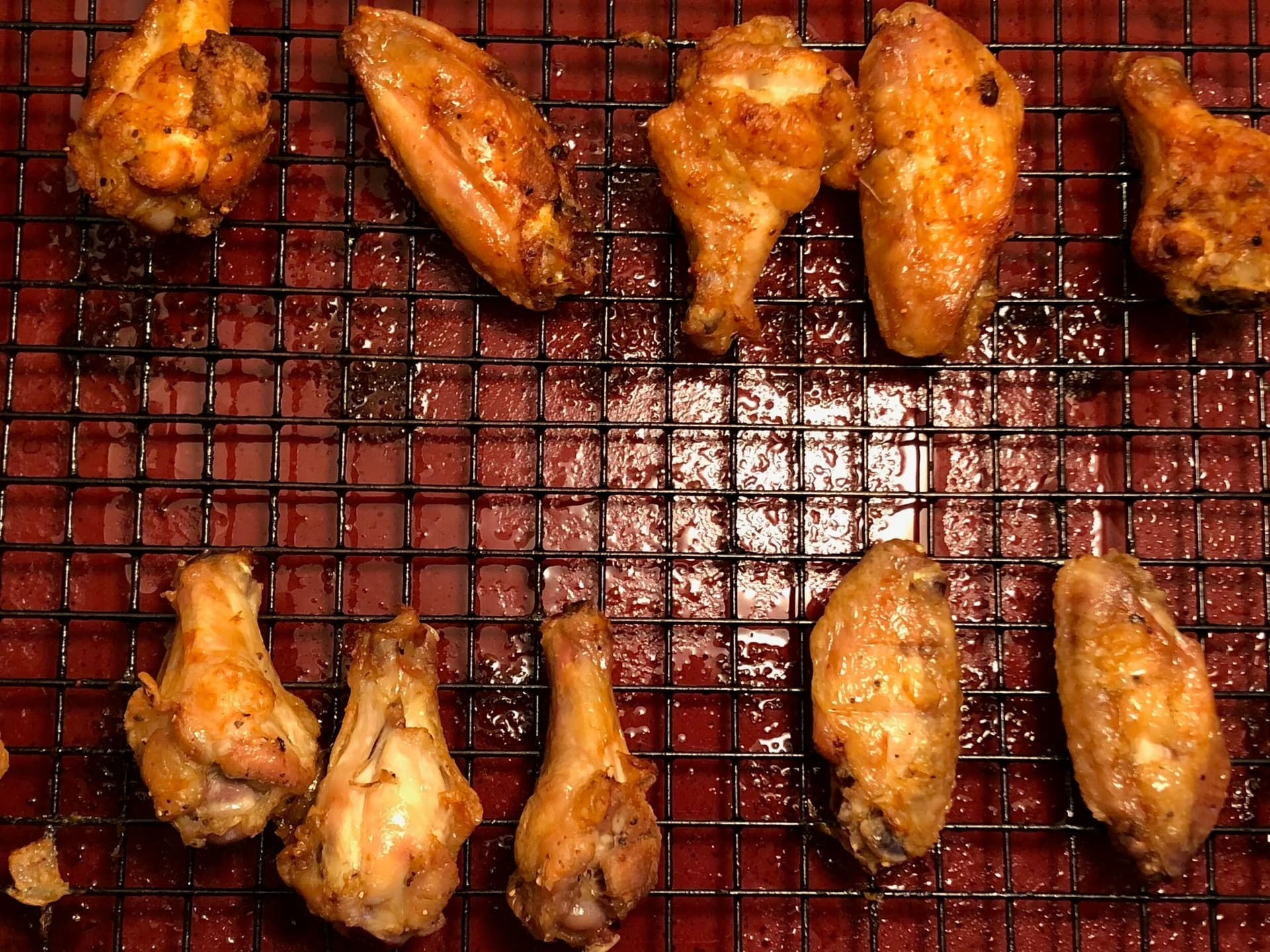 Crispy baked buffalo chicken wings on a wire rack, golden brown and glistening with sauce.