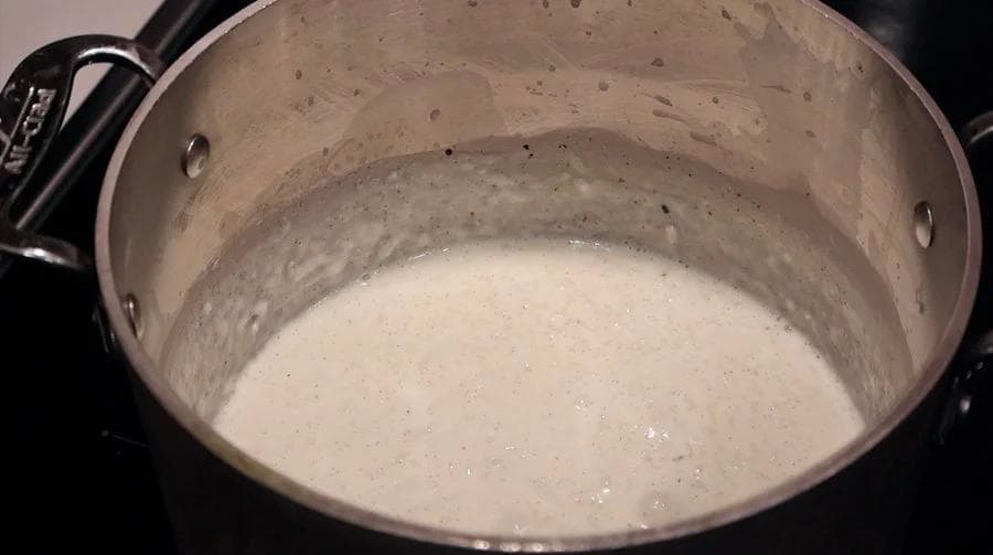Creamy rice pudding simmering in a pot, showing tender rice in a smooth, vanilla-infused milk mixture.