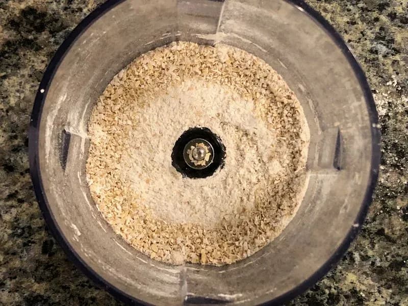Oat flour and sugar mixture combined in a food processor bowl before adding chocolate chips.