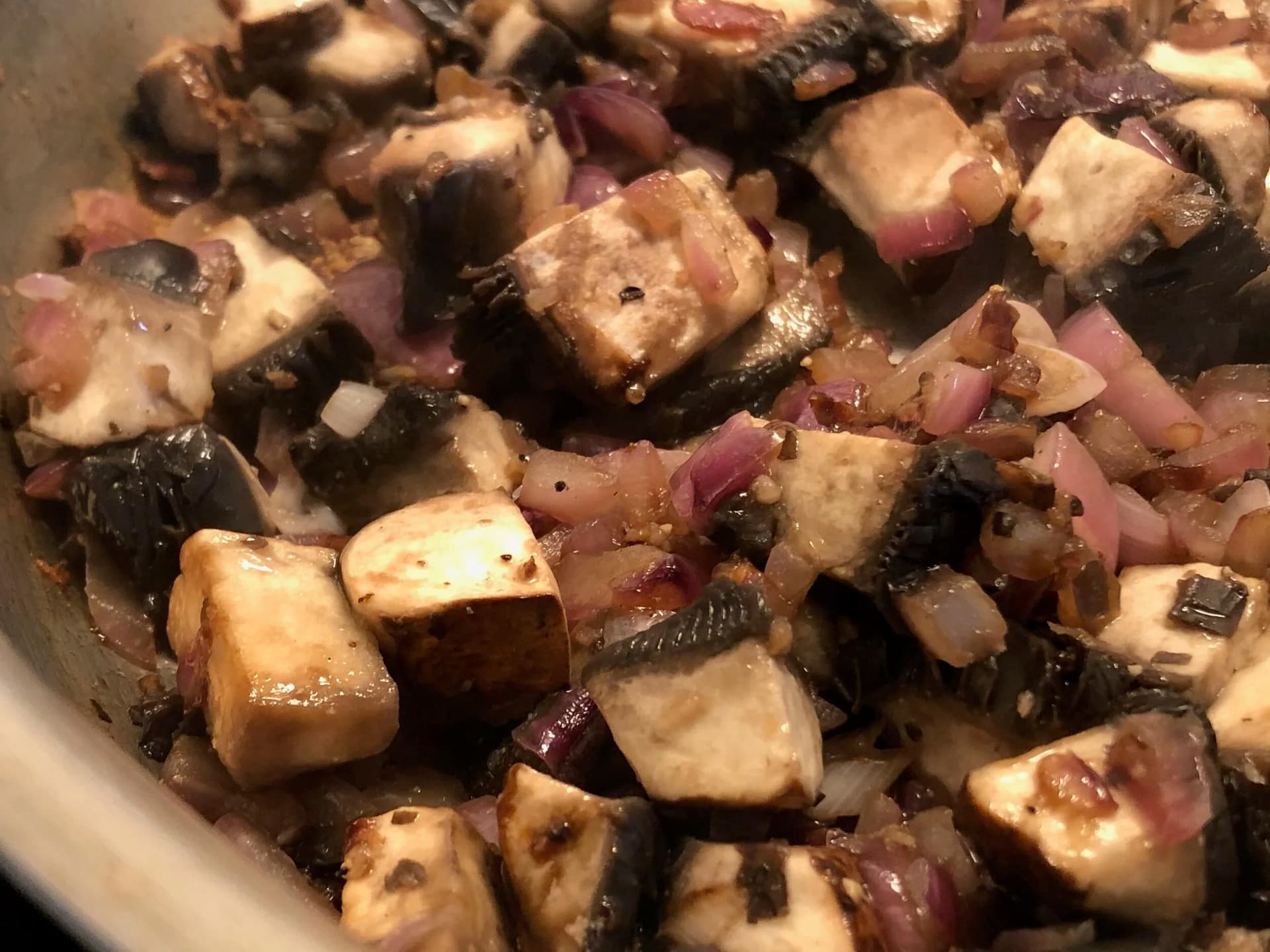 Sautéed mushrooms and red onions in a pan with olive oil, salt, pepper, and chili flakes.